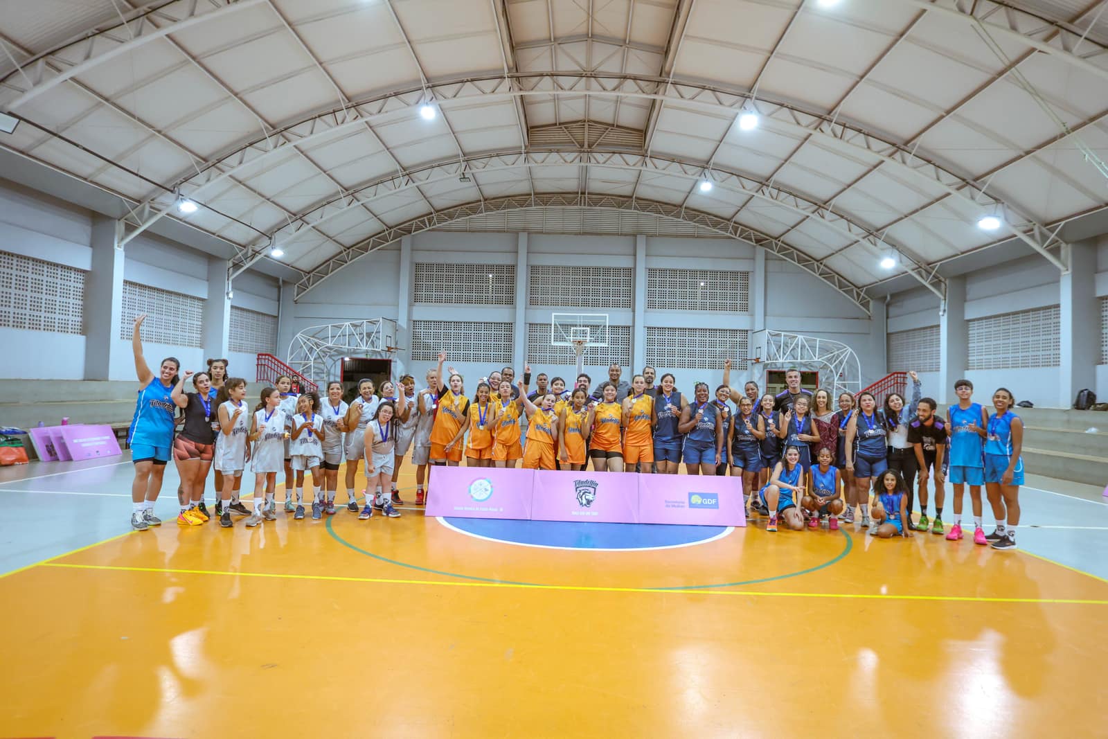 Equipes femininas reunidas em quadra no ginásio ao final de uma rodada de competição