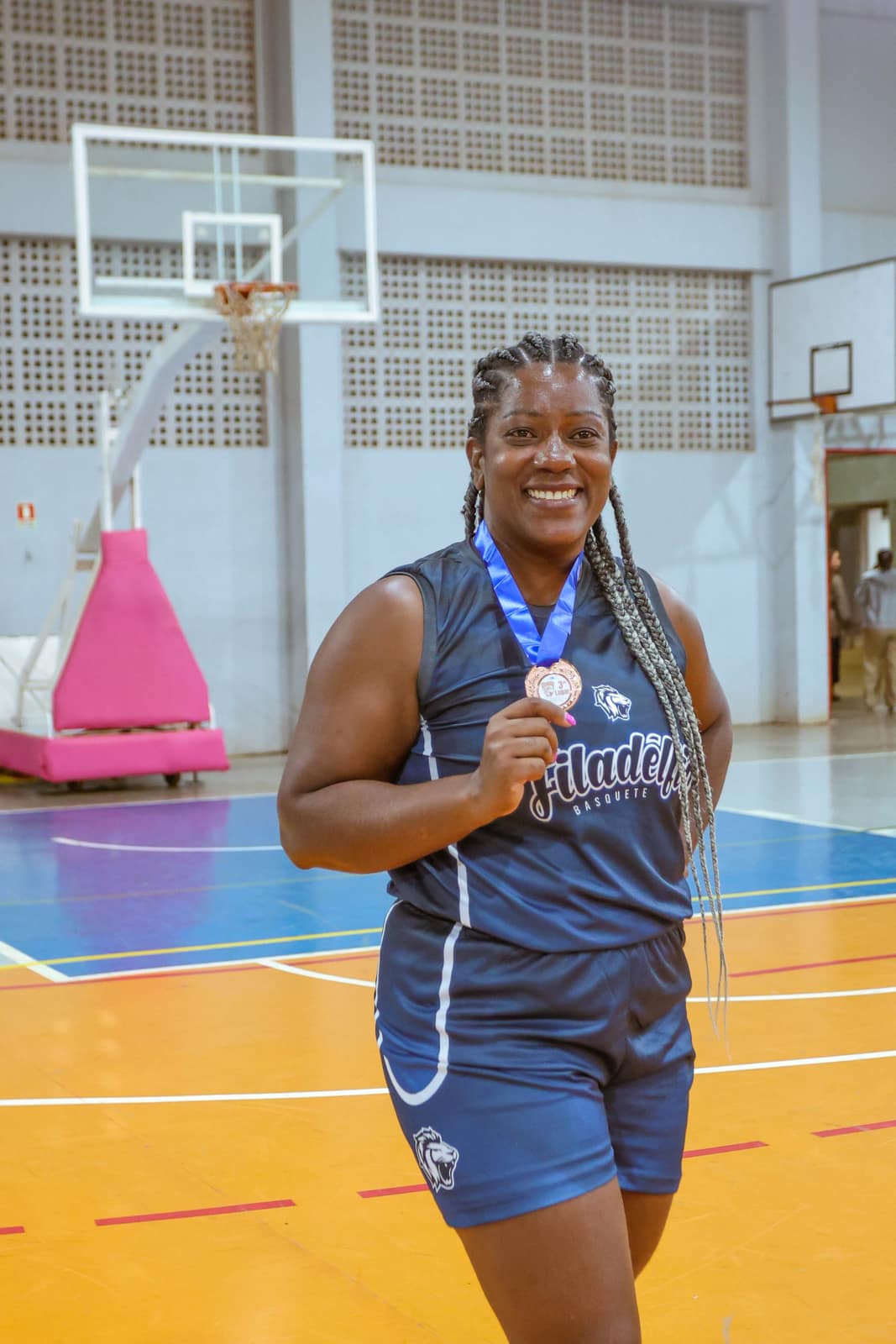 Atleta da frente feminina da Filadélfia sorri com a medalha conquistada em quadra